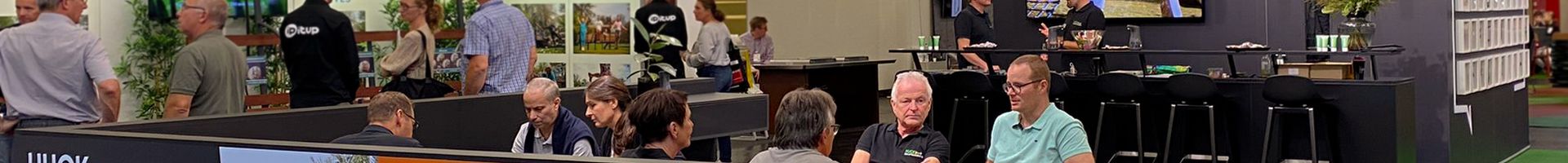 Trade fair booth, people sitting and talking, having coffee, orange trampoline.